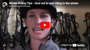 A woman wearing a riding helmet and grey jacket speaks on camera. Behind her, horse bridles and riding equipment hang on the wall. The video title reads, Winter Riding Tips – essential advice for riding in the winter without giving up.
