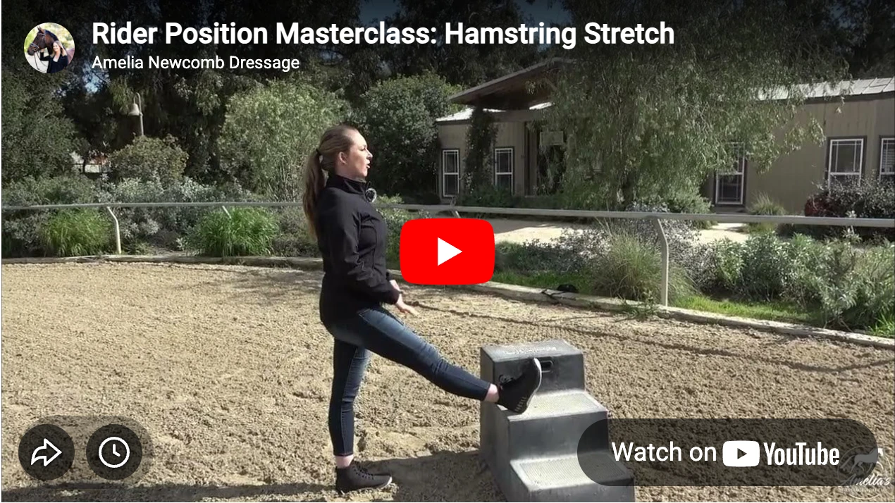A woman demonstrates a hamstring stretch by placing one leg on a mounting block in an outdoor riding arena, showcasing proper rider position, with trees and a building in the background.