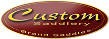 A maroon oval logo with a gold outline features the word Custom in large yellow script, and Saddlery and Brand Saddles in smaller gold letters below and above, respectively—proudly crafted for Amelia Newcomb.