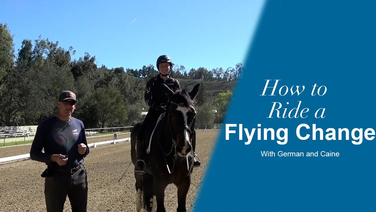 A person on horseback and an instructor stand in an outdoor riding arena. Text on the right reads: How to Ride a Flying Change with German and Caine. Trees and a clear sky are visible in the background.