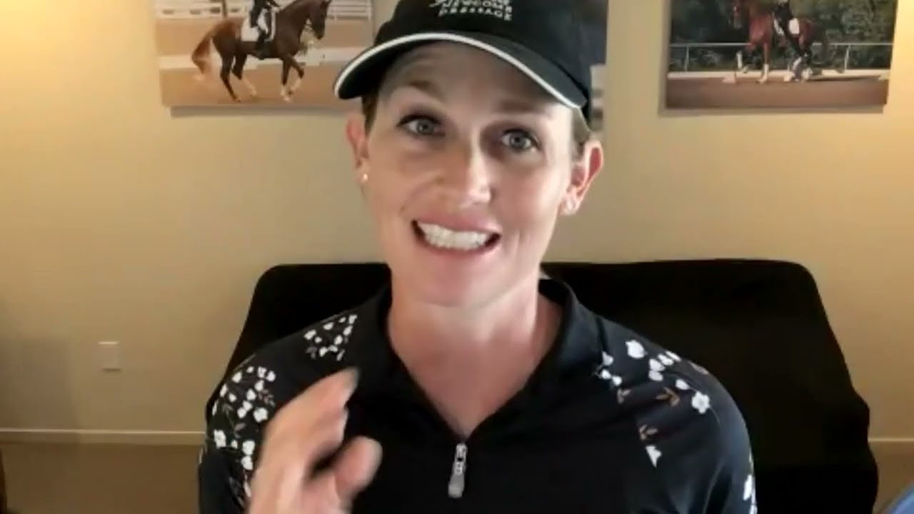 A smiling person wearing a black cap and patterned black top speaks while gesturing, with two horse-riding photos on the wall behind them.