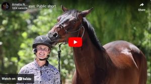 A smiling person in a helmet and patterned shirt stands next to a brown horse with a bridle, outdoors with green foliage in the background. This paused YouTube video is part of an introduction to Amelia's Horses, with visible play and share buttons.