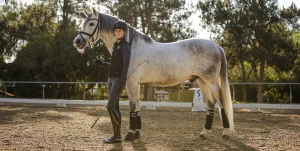 Amelia Newcomb posing and smiling with her horse Mercurio.