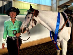 Strides member Cindy Kerr wearing Western competition clothing posing with her horse.