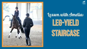 A riding instructor watches a rider on a horse practicing dressage indoors, focusing on a leg-yield exercise. Text on a blue background reads, Lesson with Amelia: Leg-Yield Staircase to improve leg-yields.