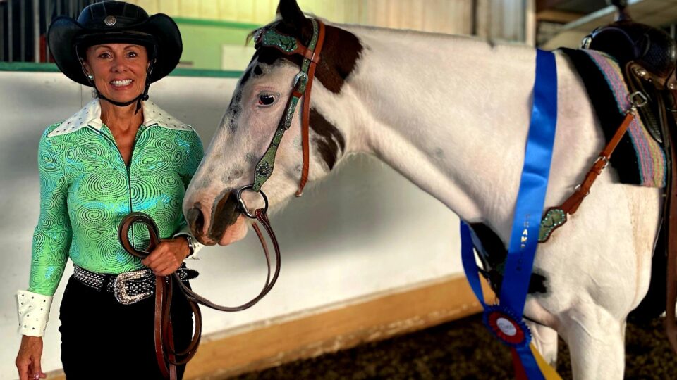 Strides member Cindy Kerr wearing Western competition clothing posing with her horse.